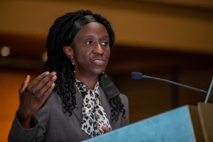 Female standing behind a podium, giving a presentation