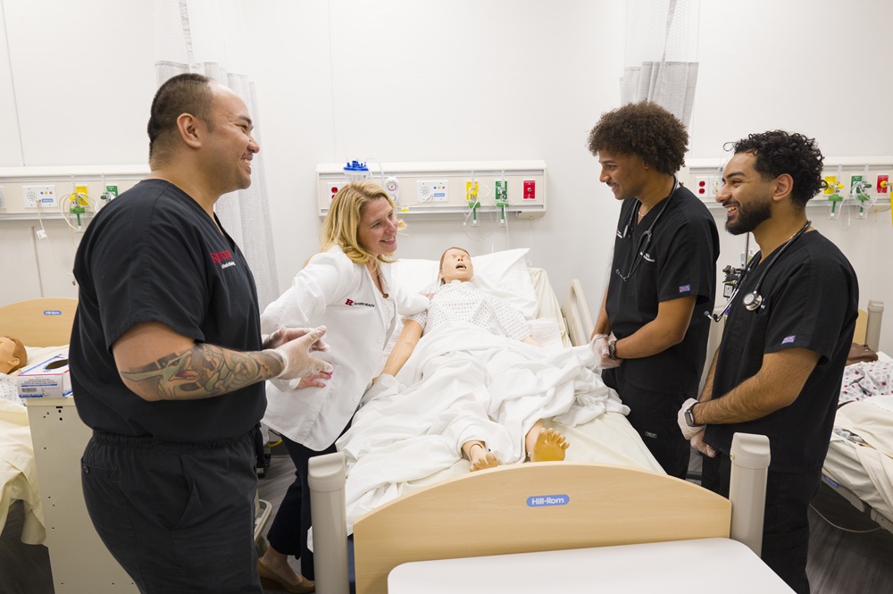 People in hospital room over test mannequin