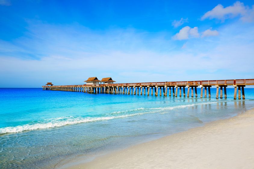 image of a wooden pier stretching out over a calm ocean with a clear blue sky