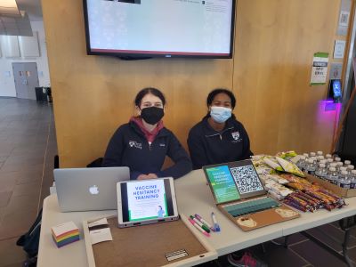 two students sitting at vaccine information booth